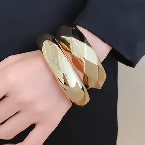 Macro view of thick golden geometric acrylic bangles worn on wrist for a bold fashion look