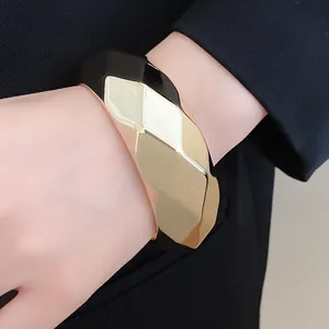 Detailed view of a faceted geometric acrylic bangle in bold black and gold finish