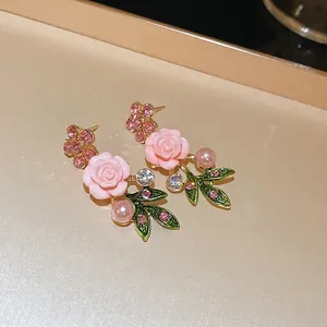 Detail view of vintage pink fabric rose earrings with pearls and crystals.