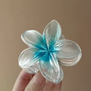 Close-up of elegant translucent plumeria flower hair claw clip with blue gradient design