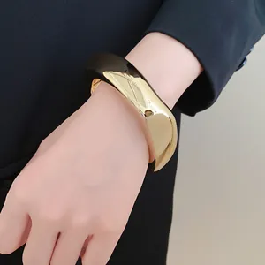 Macro view of wide geometric acrylic chunky bangle in black and gold metallic finish