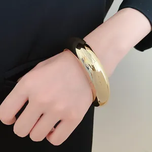 Detailed view of a chunky gold acrylic geometric cuff bracelet styled on a model's wrist.