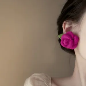 Dettaglio ravvicinato di un orecchino a rosa floccata rosa brillante indossato da una modella
