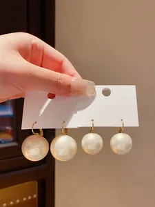 Dettaglio di eleganti orecchini pendenti con grandi perle bianche e cerchi d'oro