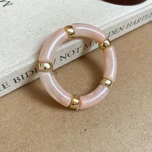 Macro detail shot of a pink marbled acrylic segment bracelet with elegant gold beads