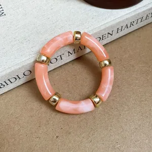 Detail view of pink marbled acrylic bracelet with gold-tone spacers on a book background
