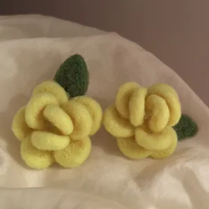Primo piano della consistenza morbida degli orecchini a lobo a forma di fiore giallo floccato.