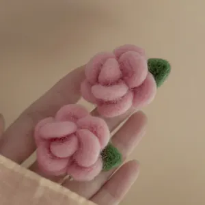 Vista macro da vicino di delicati orecchini a forma di rosa in feltro rosa fatti a mano