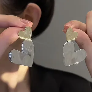 Detailed macro view of heart-shaped metal stud earrings with high-polish finish.
