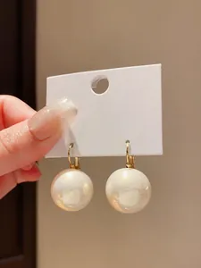 Primo piano di orecchini di perle in stile francese con elegante chiusura dorata.