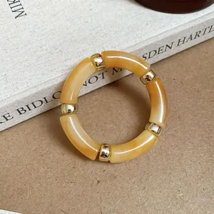 Close-up detail of a marbled amber acrylic tube bracelet with gold metal spacers