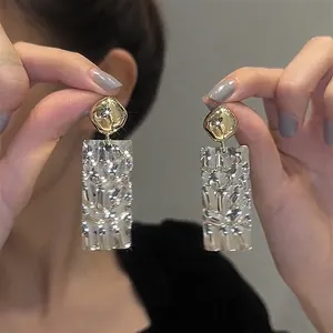 Close-up detail of sparkly crystal rectangle drop earrings featuring elegant gold metallic tops
