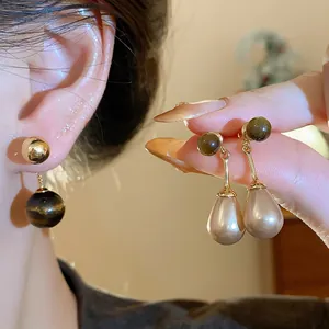 Close-up of retro tiger eye and teardrop pearl earrings with real gold plating finish