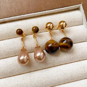 Detailed close-up showing tiger eye stone and teardrop pearl earrings in a jewelry box.