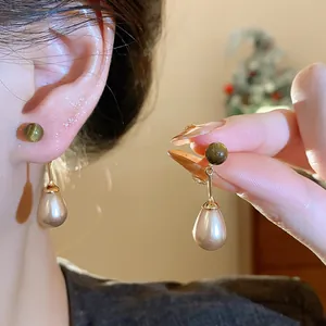 Macro view of retro tiger eye stone and waterdrop pearl earrings in elegant gold plating