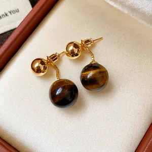 Exquisite close-up detail of gold-plated tiger eye stone drop earrings in a jewelry box.