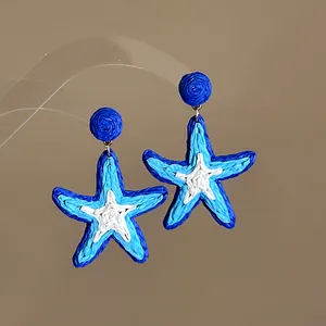 Detail view of blue and white woven starfish earrings with stainless steel needle pins.