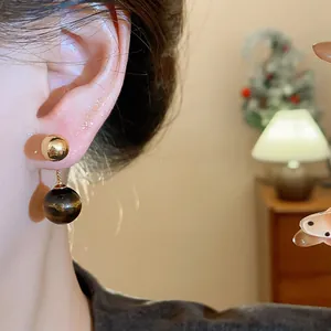 Macro detail of vintage tiger eye stone drop earrings with premium real gold plating.