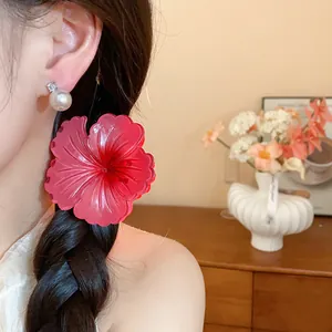 Detailed macro shot of a vibrant red pleated flower hair claw clip on braided dark hair