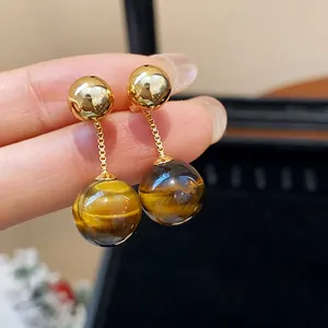 Close-up of vintage gold plated earrings with round tiger eye stone drops.