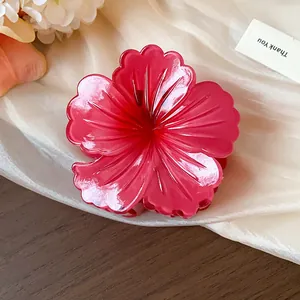 Close-up of a large red hibiscus flower hair claw clip with pleated texture on silk background