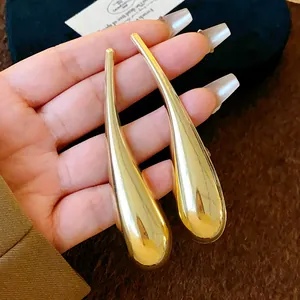 Primo piano dei grandi orecchini a goccia d'oro irregolari con finitura lucida