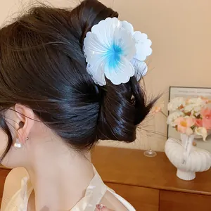 Close-up view of a large white and blue gradient flower hair claw clip worn in hair