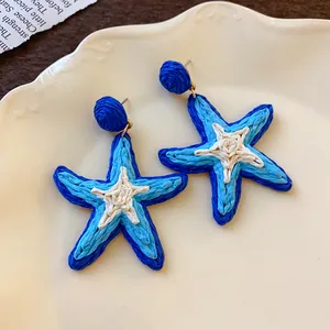 Close-up of handmade woven blue and white starfish earrings with high quality steel needles