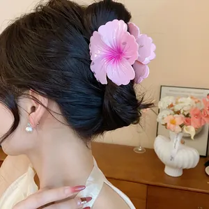 Macro view of a large pink hibiscus flower hair claw clip styled on a brunette hair bun