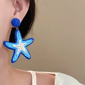 Detailed macro view of blue and white hand-woven star earring for beach vacation style.