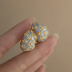 Detailed view of vintage enamel C-shaped earrings featuring gold rose and crystal accents.