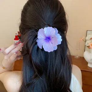Purple flower hair claw clip with pleated petals worn on long dark hair in a lifestyle setting