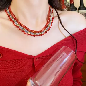 Detailed view of an ethnic beaded lace necklace on a model wearing a festive red sweater