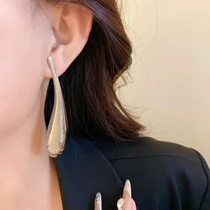 Primo piano di un orecchino a goccia d'argento irregolare indossato da una modella elegante