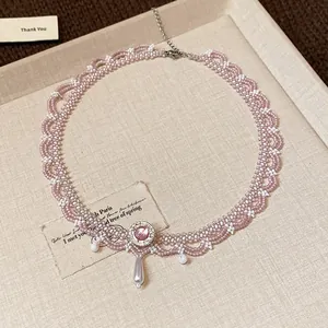 Macro detail of a pink glass beaded lace choker with a crystal and pearl drop pendant.