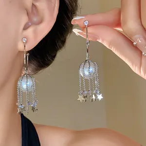 Gros plan d'élégantes boucles d'oreilles en argent en C avec perles et franges d'étoiles
