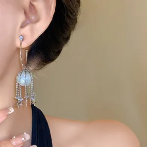 Détail de boucles d'oreilles en argent avec perle et pompons étoiles sur l'oreille