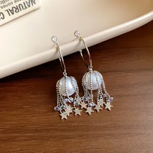 Détail de boucles d'oreilles à franges étoiles en argent avec perles et cristaux.