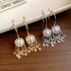 Vue détaillée de boucles d'oreilles créoles en C avec perles et glands d'étoiles pendants.