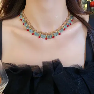 Detailed view of elegant beaded lace necklace with red and blue glass beads on neck.
