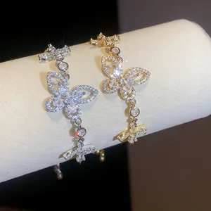 Close-up of elegant gold and silver zirconia butterfly bracelets on a jewelry display stand.