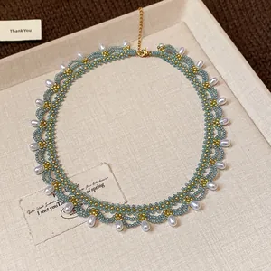 Close-up detail of a blue and gold beaded lace necklace featuring elegant pearl drops