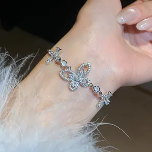 Close-up of a sparkling zircon butterfly bracelet worn on a wrist with white feathers