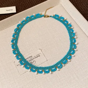 Detailed macro view of turquoise glass bead lace pattern with white teardrop accents.