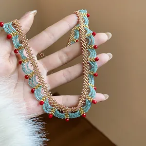 Close-up of handmade beaded lace necklace with light blue, gold, and red glass beads.