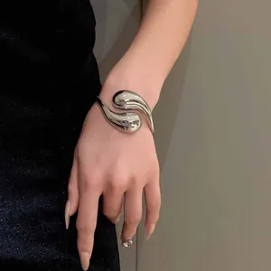 Brazalete metálico plateado escultural con un atrevido diseño fluido en forma de gota