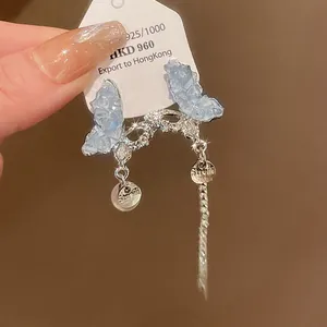Close-up of elegant crystal butterfly earrings with long silver tassels and pearls