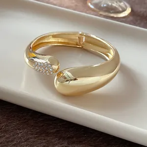 Detalle del brazalete de gota en oro grueso con pavé de strass brillante en un extremo