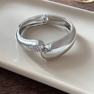 Detalle de brazalete plateado grueso en forma de gota con detalles de pedrería pavé