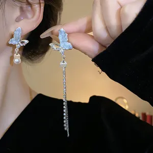 Close-up of asymmetric butterfly tassel earrings with rhinestones and pearls